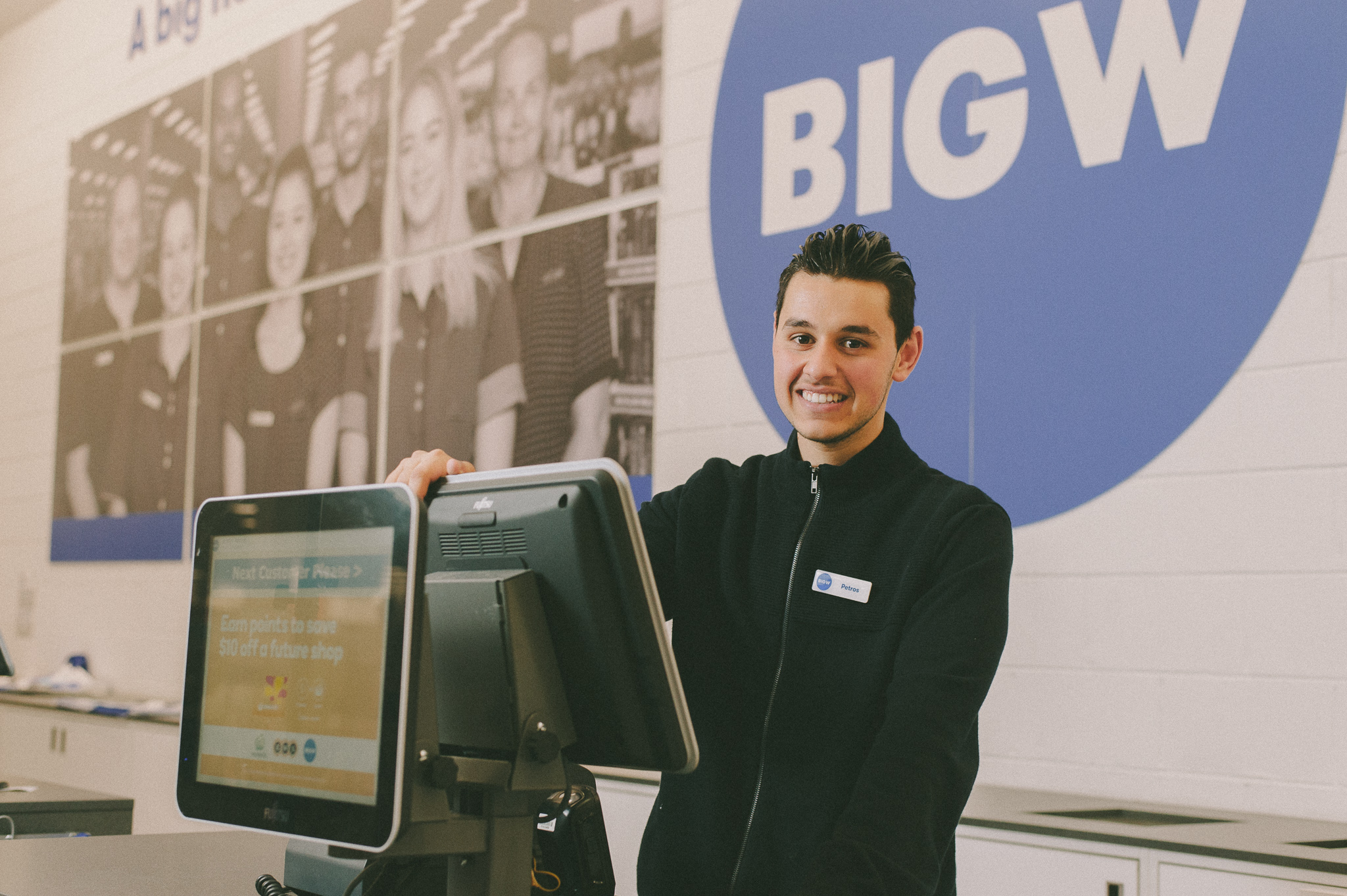 Petros standing at work in front of Big W sign at a cash register