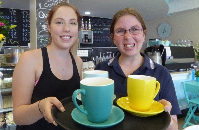 2 young women standing in a cafe holding coffee cups in a cafe