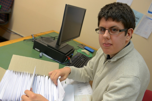 young man sitting at a desk going through paper work