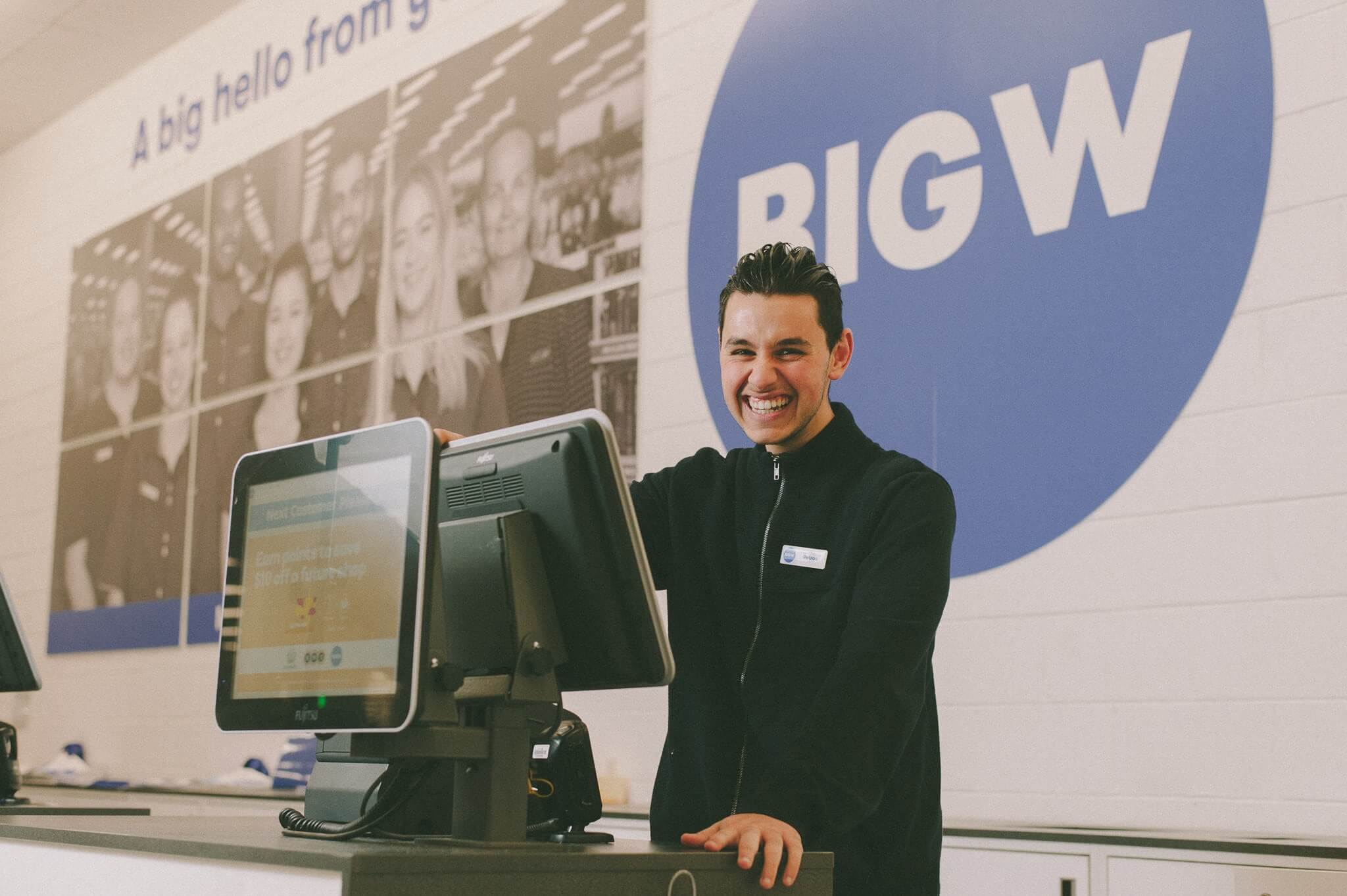 Petros standing at work in front of Big W sign at a cash register